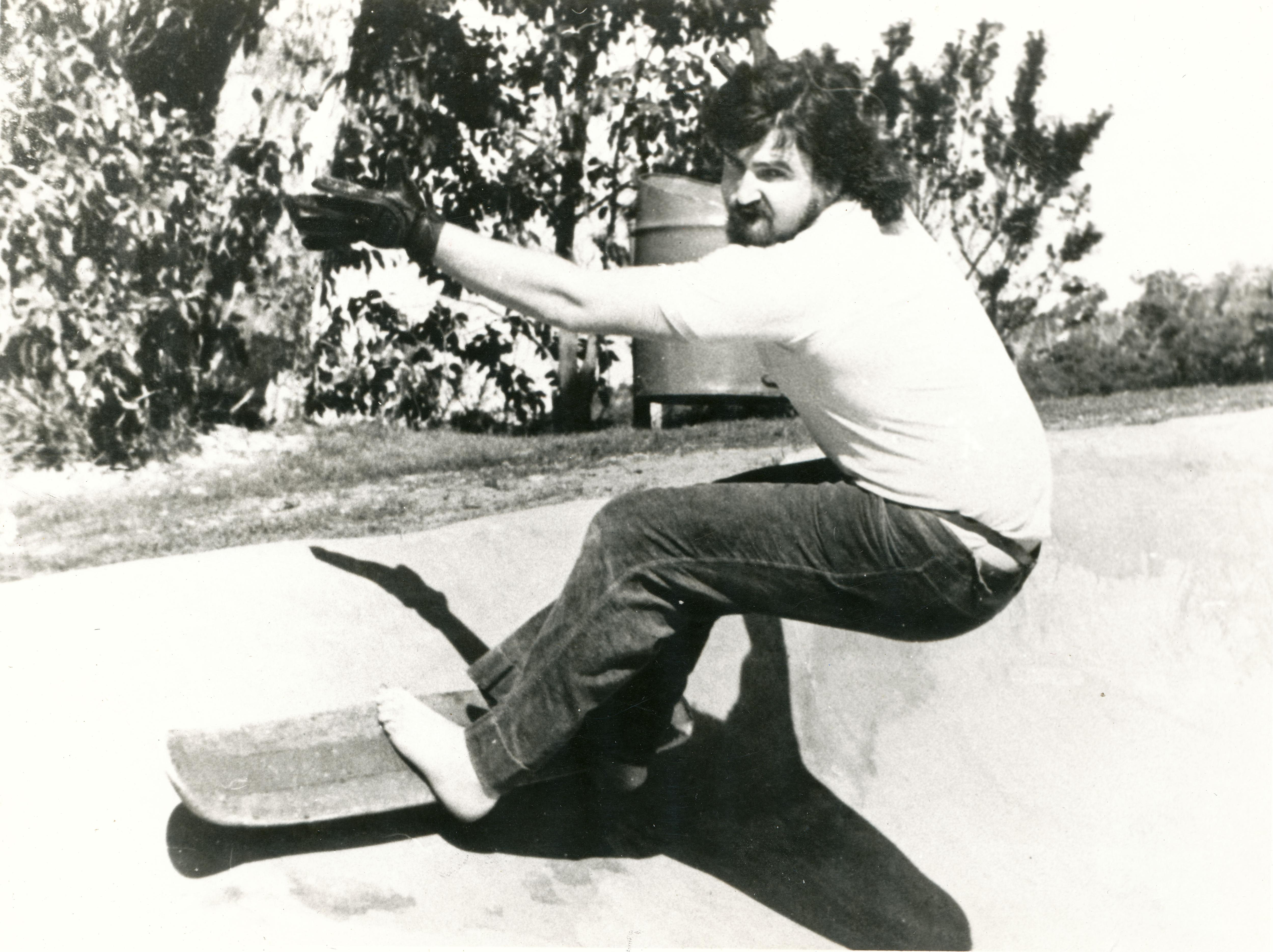 Un hombre descalzo da un giro en una patineta. 