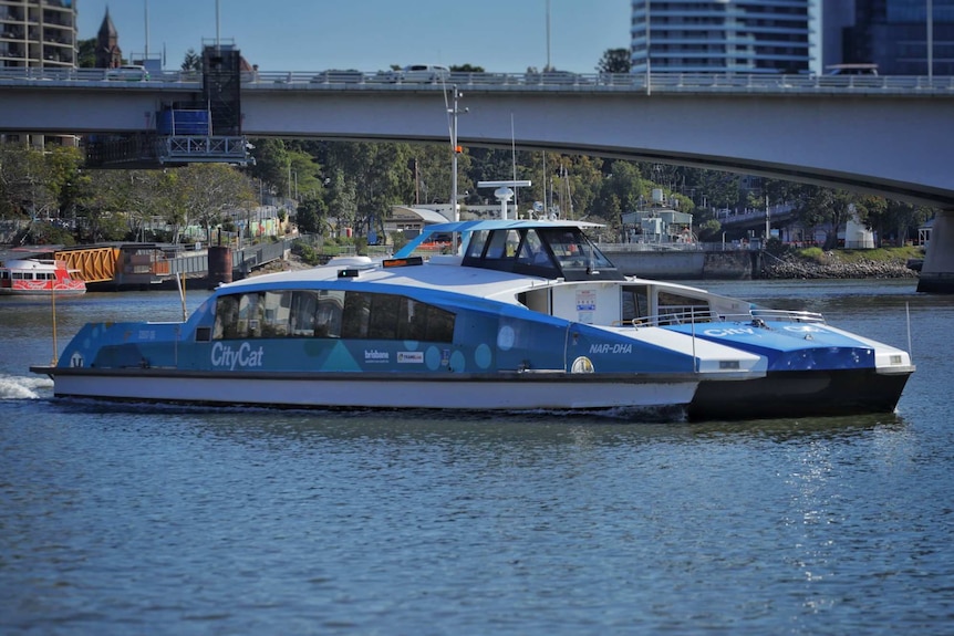 Blue City Cat ferry called Nar-Dha on Brisbane river, with the South East Freeway and South Bank in view.