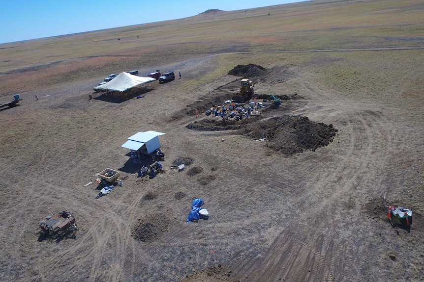 An aerial shot of a dig site, with holes in the ground and excavators.