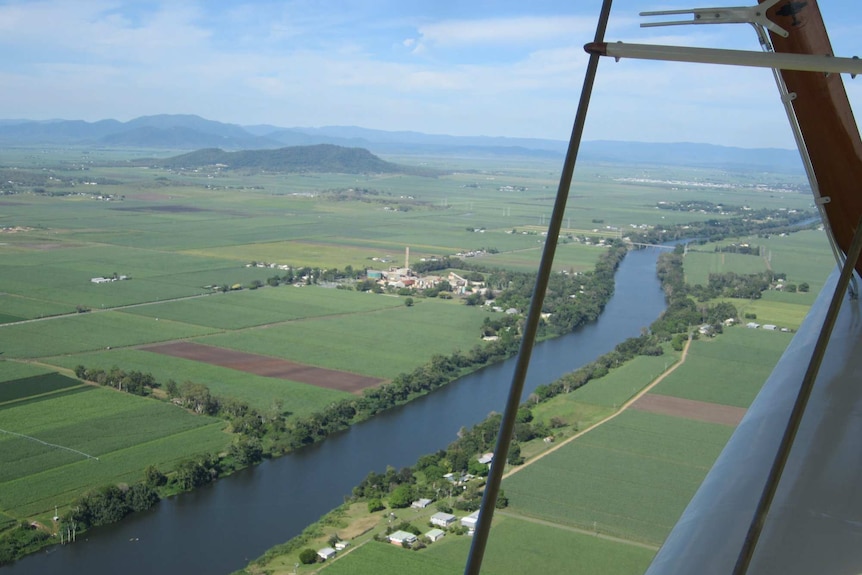 an aerial view of cane fields, roads and a sugar cane mill