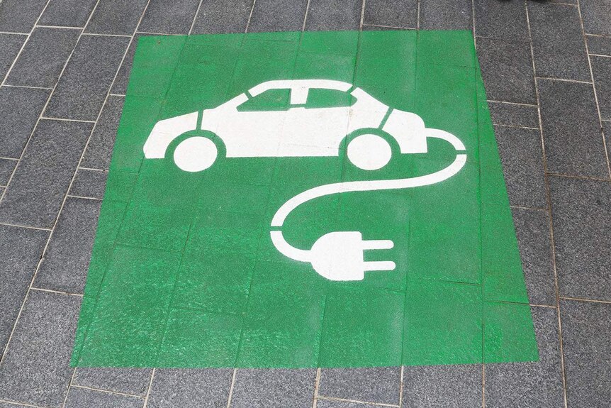 Green and white sign for charging station for an electric car parking space.
