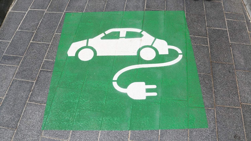 Green and white sign for charging station for an electric car parking space.