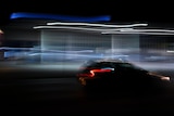A photo of a car being driven at night with a blurry night trail.