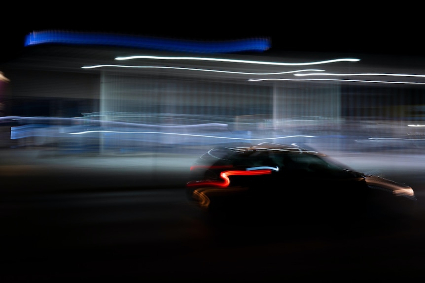 A photo of a car being driven at night with a blurry night trail.