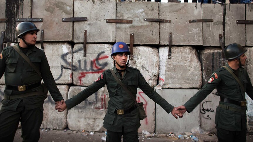 Egyptian soldiers stand in line as anti President Mohamed Morsi protesters stand on top of a barricade.