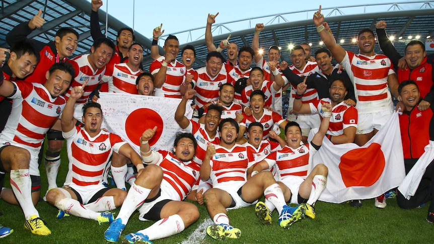 Japan players celebrate with the flag after Springboks scalp