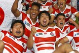 Japan players celebrate with the flag after Springboks scalp