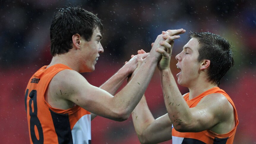 Tow footballers embrace during a match in the rain.