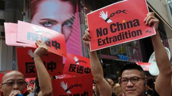 Demonstrators hold up red signs saying "no China extradition".