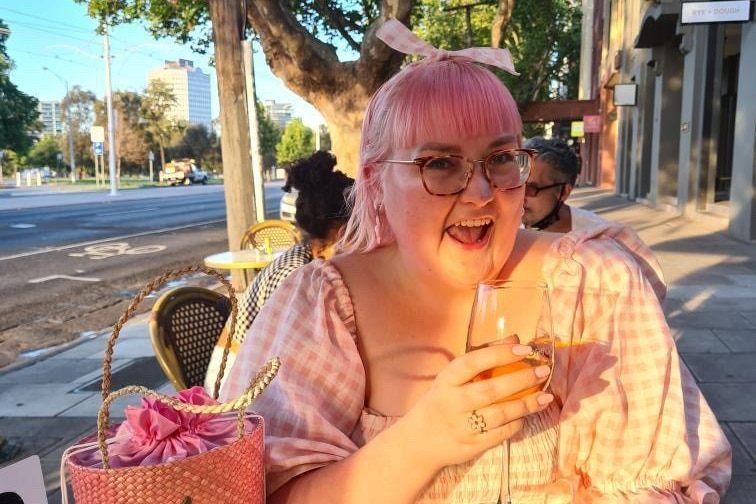 a woman drinking wine and smiling in a pink dress