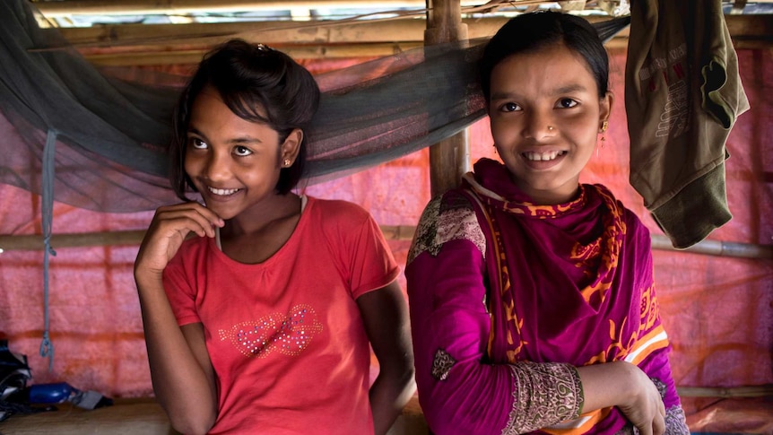 Two young girls laugh in a makeshift hut