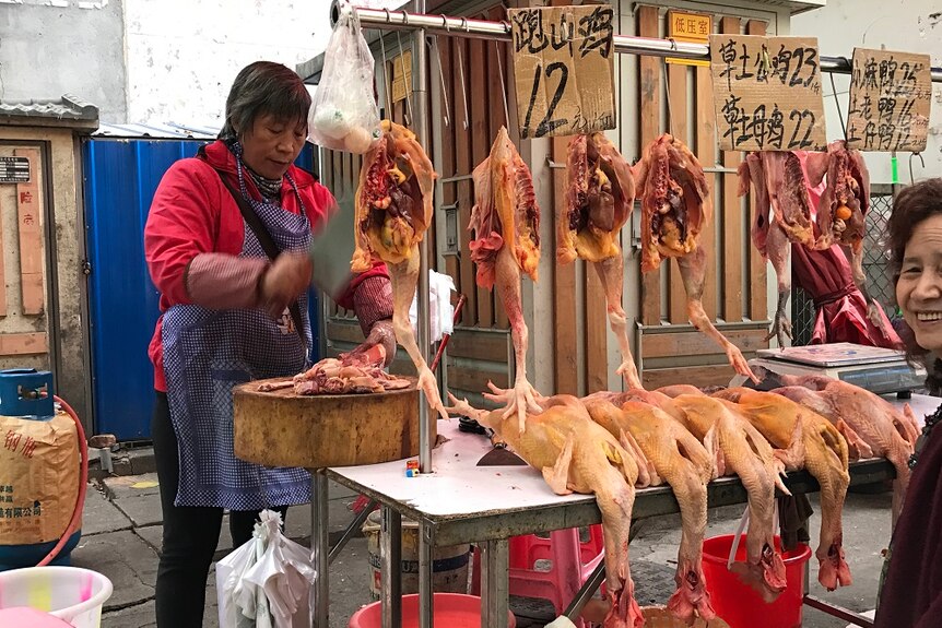 A woman chopping meat in a Chinese street stall.