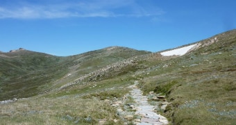 Walking trail winds up towards Mt Kosciuszko on a sunny day.