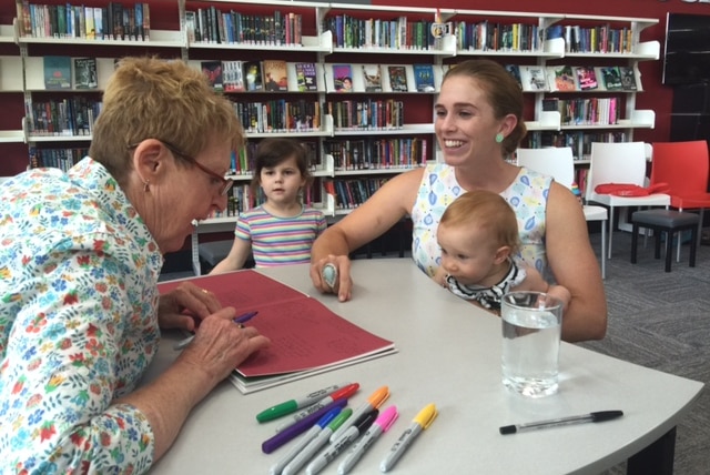 Mem Fox signs a book for a mother and small child.