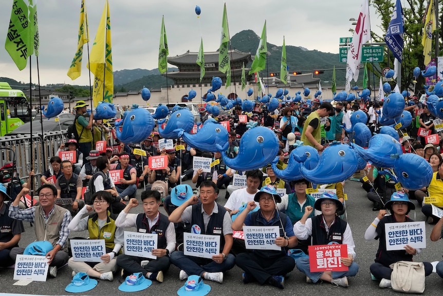 Protesters hold up inflated whales as they stage a rally against the decision to release treated radioactive water.