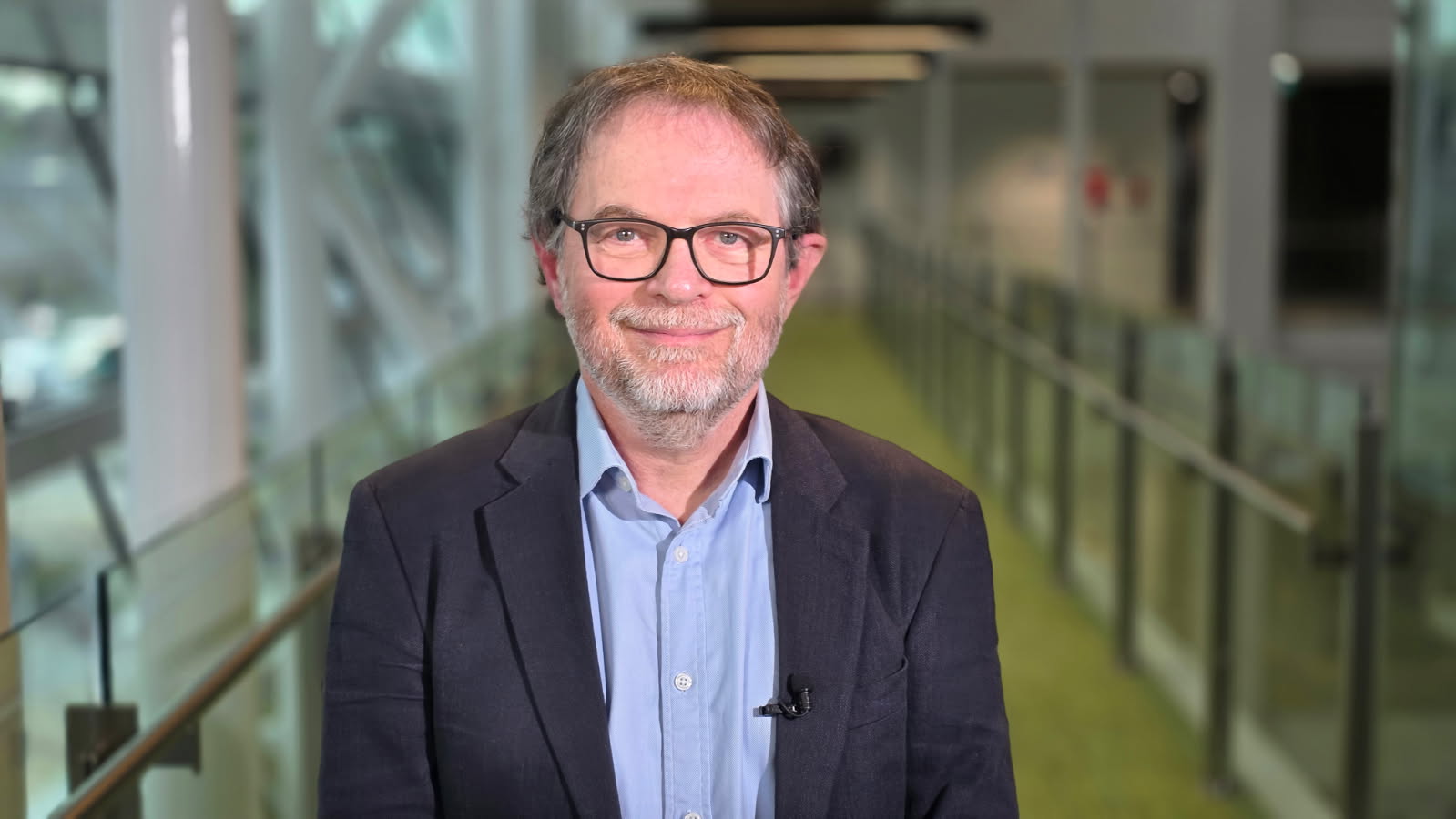 Professor Justin Zobel, computer scientist, looks at the camera smiling. He wears glasses and a black jacket