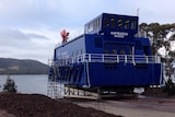 Huon Aquaculture launches the first of four new feeding barges at Margate, south of Hobart.