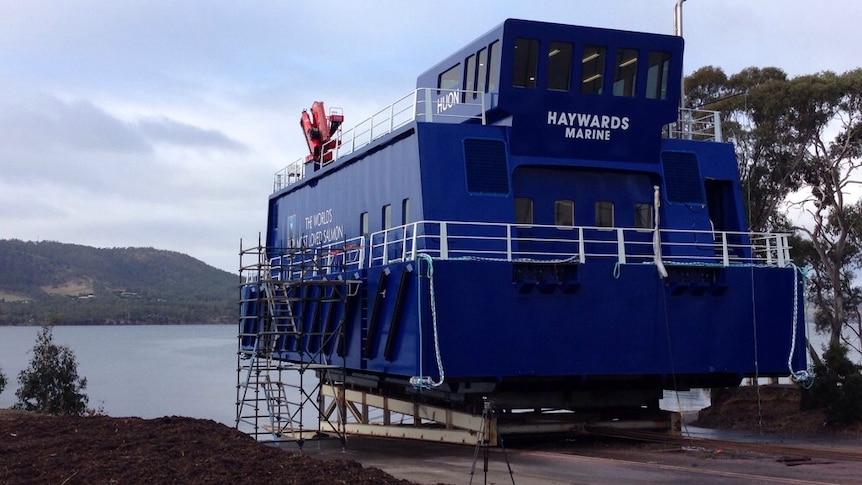 Huon Aquaculture launches the first of four new feeding barges at Margate, south of Hobart.