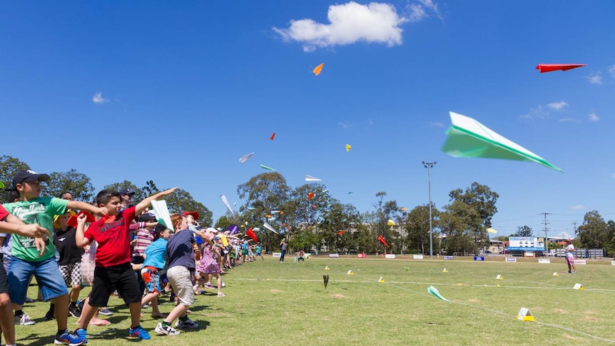 Children lining up to throw paper planes.