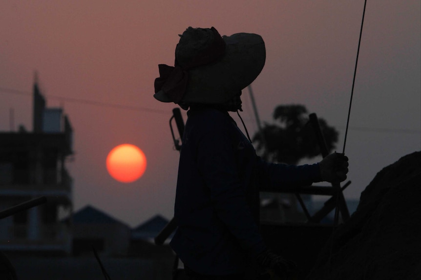 Sun rising behind a Cambodian construction worker in Phnom Penh.