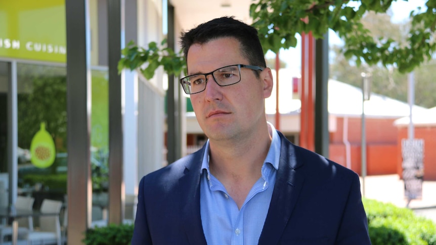 Zed Seselja stands in front of some shops and restaurants in Canberra.