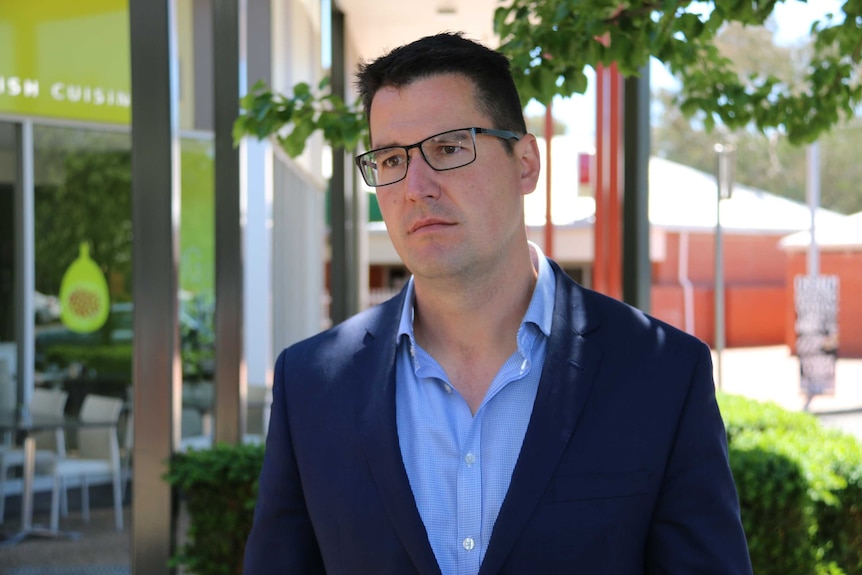 Zed Seselja stands in front of some shops and restaurants in Canberra.