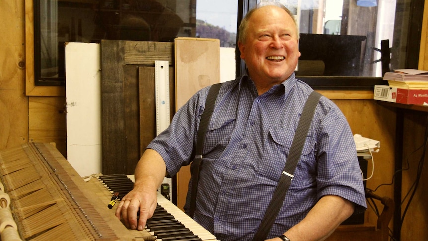 Robert Tucker sitting at a piano board he is fixing at his home in Ulverstone.