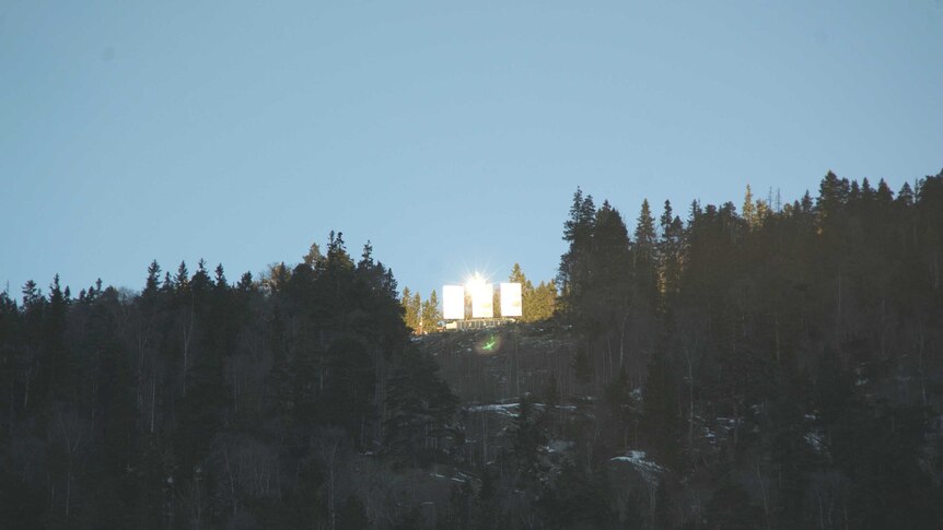 Three giant heliostats reflect the sun from a nearby mountain down into the town square.