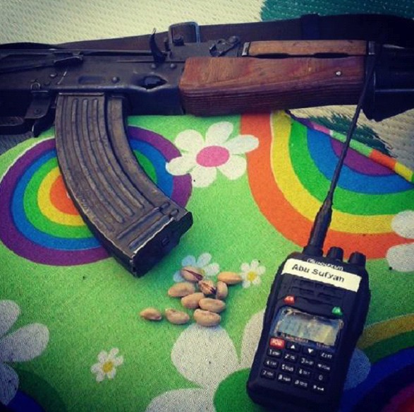 A machine gun, pistachios and a walkie talkie sit on a table covered with a bright rainbow.