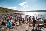 Surfers walk to the water to participate in the paddle out