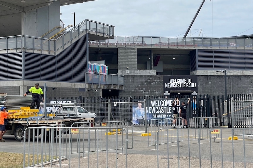 Two men putting up a 'Welcome to Newcastle Paul' sign ahead of Paul McCartney's Newcastle show