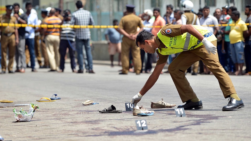 A Sri Lankan police officer examines the scene of a shooting in the capital Colombo
