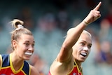Adelaide Crows AFLW players Caitlin Gould (left) and Erin Phillips run away smiling after a goal in their preliminary final.