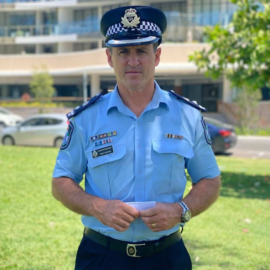 A uniformed police officer standing on a grassed area with a police hat on