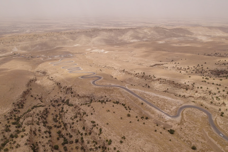 A dirt road snakes through a dry brown landscape