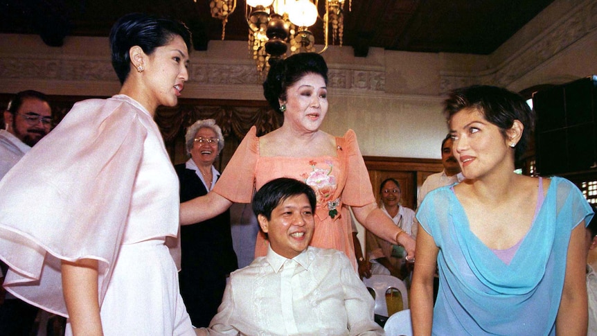 Imelda Marcos in a peach-coloured gown surrounded by her two daughters, with her son in the foreground
