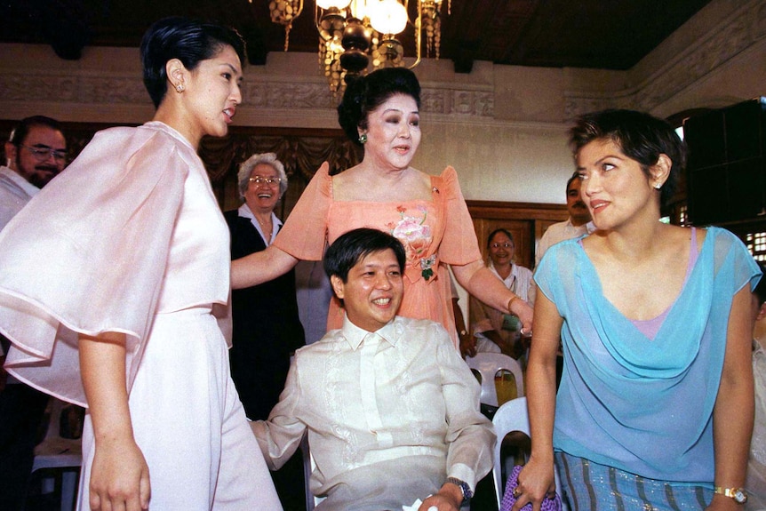 Imelda Marcos in a peach-coloured gown surrounded by her two daughters, with her son in the foreground