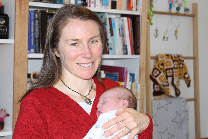 A woman holds a young baby.