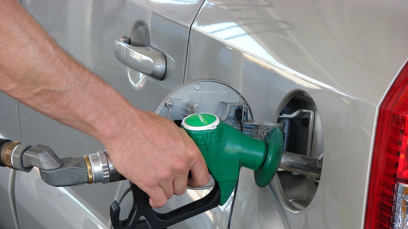 Hand pumping fuel into car at service station.