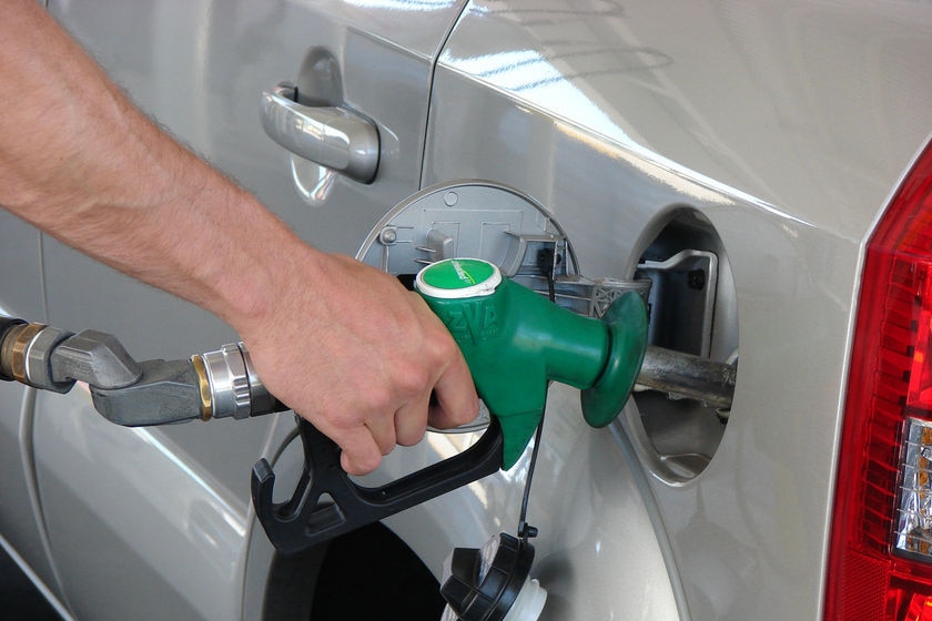 A hand holds a fuel pump as it refuels a car.