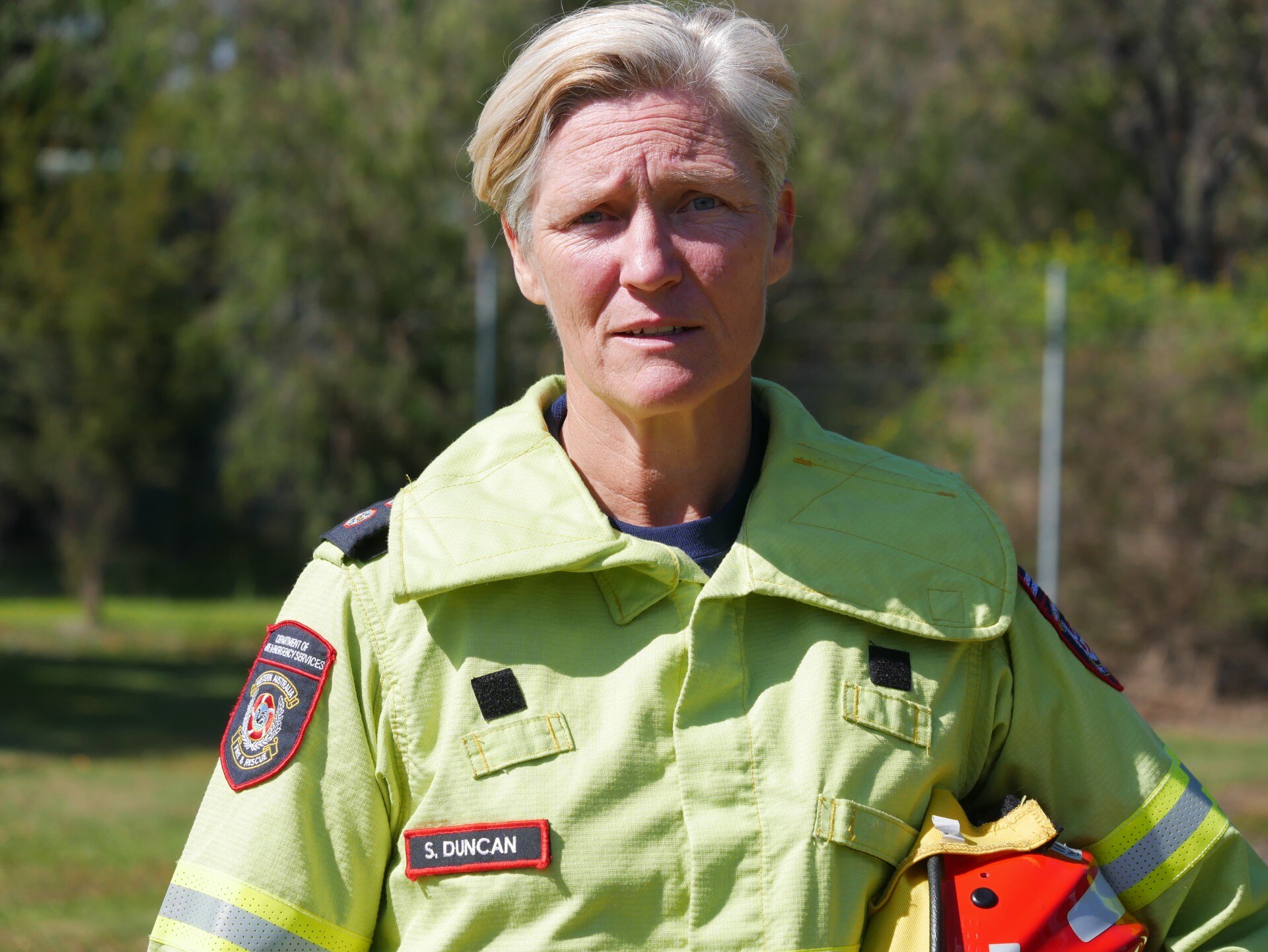 Un bombero uniformado y con un casco en la mano.