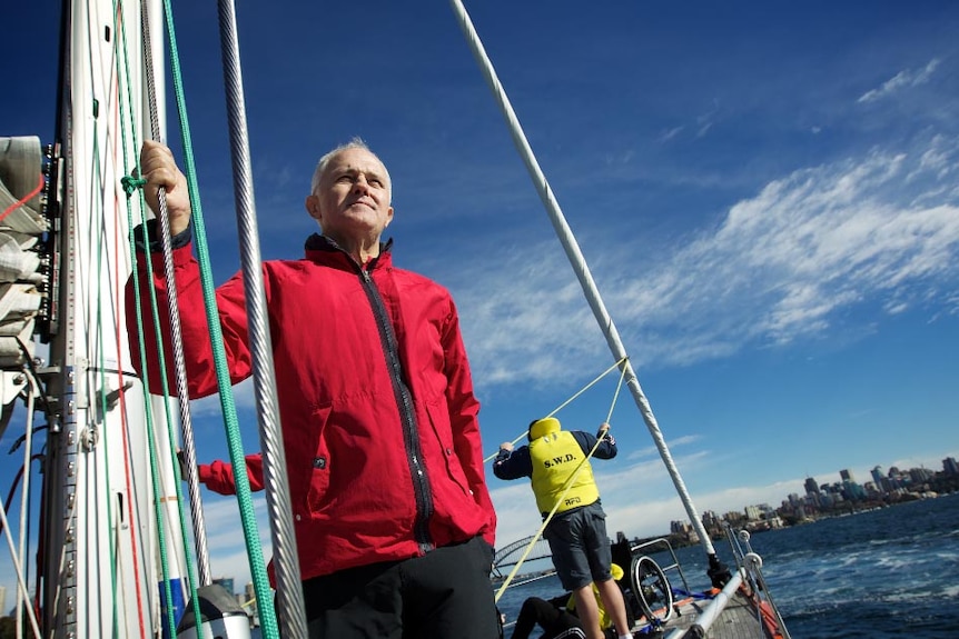 Malcolm Turnbull stands on a yacht holding onto a stay while sailing on Sydney Harbour.