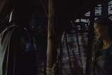 A scene from Mandalorian, with two characters shrouded in darkness.