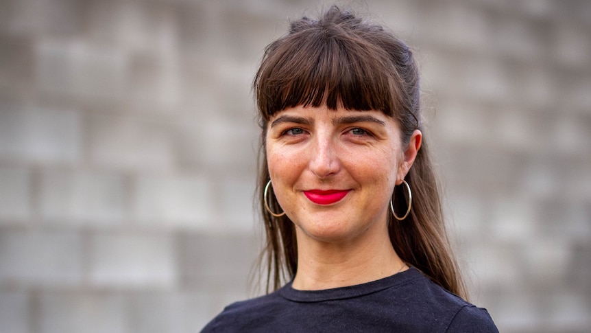 Rachel Day, in front of a textured grey wall.