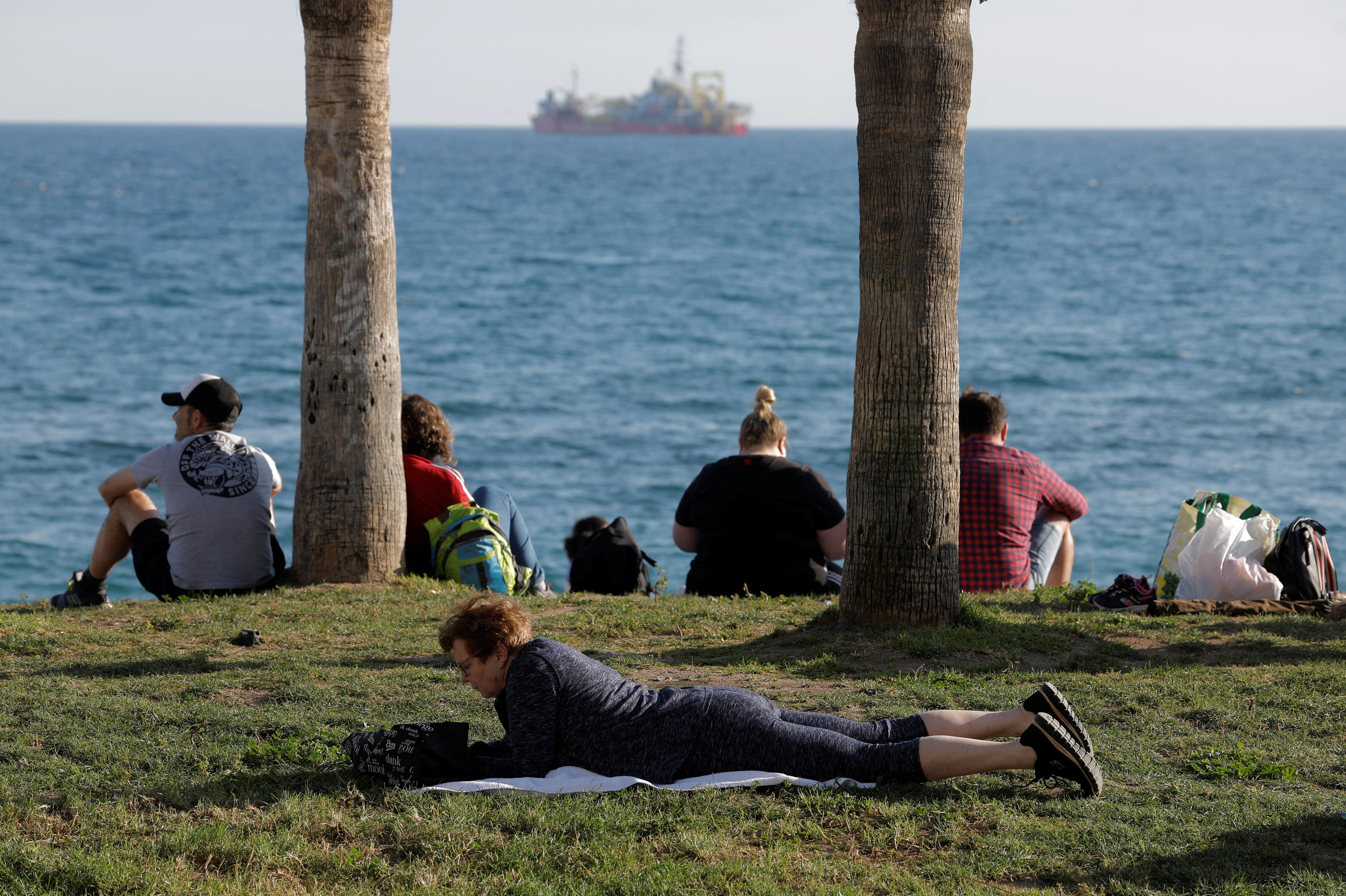 People enjoy the sun in front of the sea.