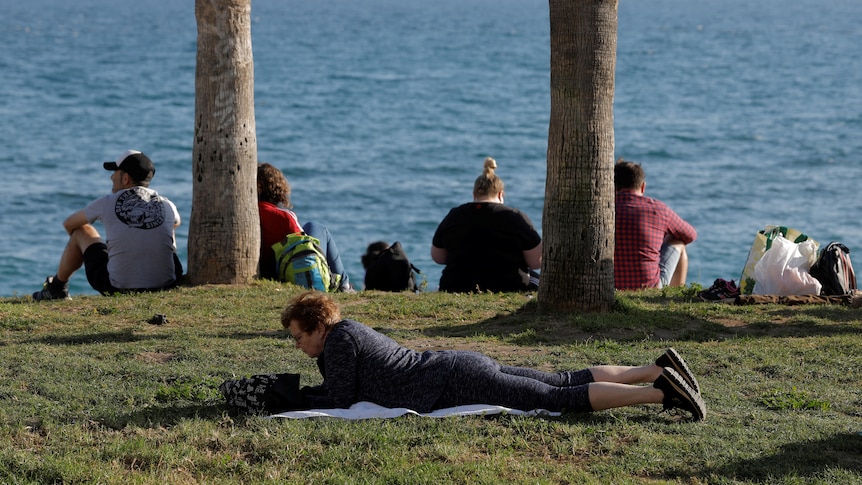 People enjoy the sun in front of the sea.