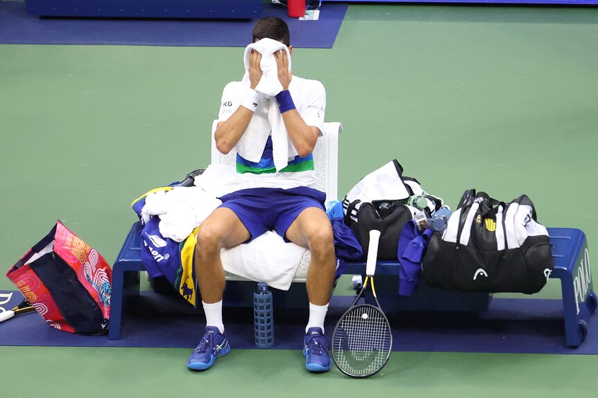 Novak Djokovic covers his face with a towel