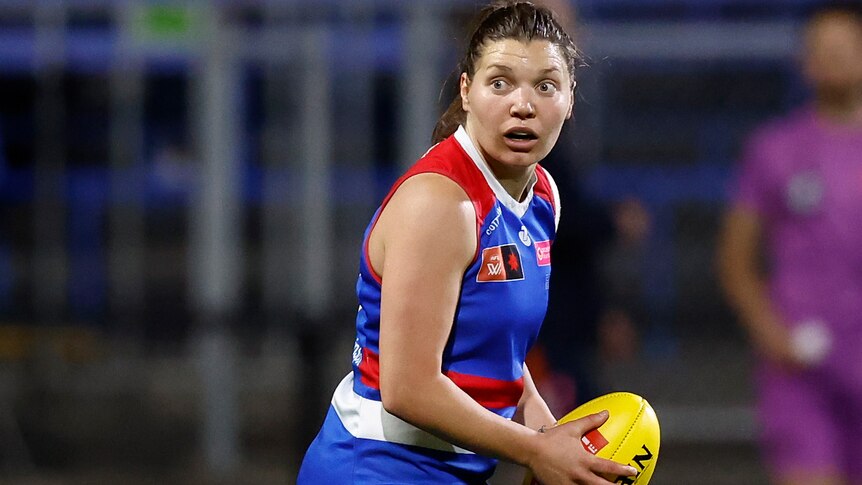 A Western Bulldogs AFLW player holds the ball during a match in 2023.