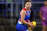 A Western Bulldogs AFLW player holds the ball during a match in 2023.