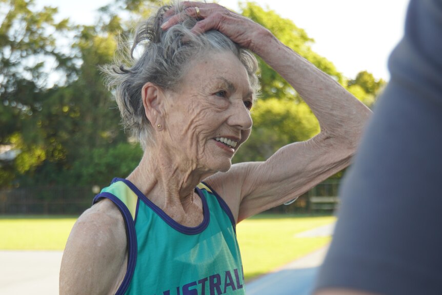 An older woman in athletics gear smiles.